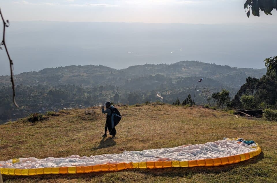 Gleitschirmpilot mit ausgelegtem Schirm bei der Startvorbereitung am Startplatz Kilima mit Blick über das Kerio Valley in Kenia.